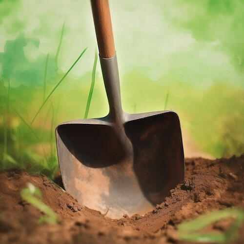 A circular image of a wood handled shovel stuck into brown dirt against a background of grassy green.